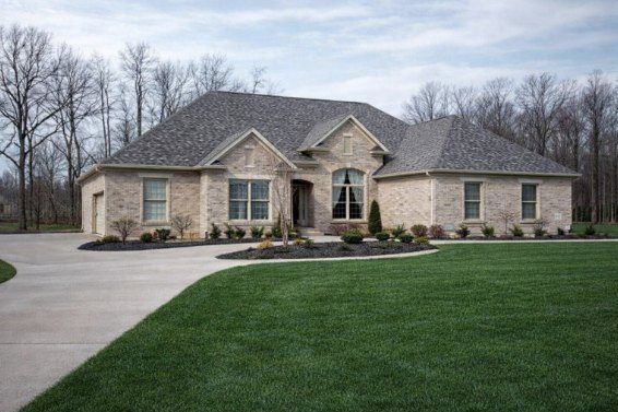 Oakridge, a light stone ranch custom home with a curved concrete driveway
